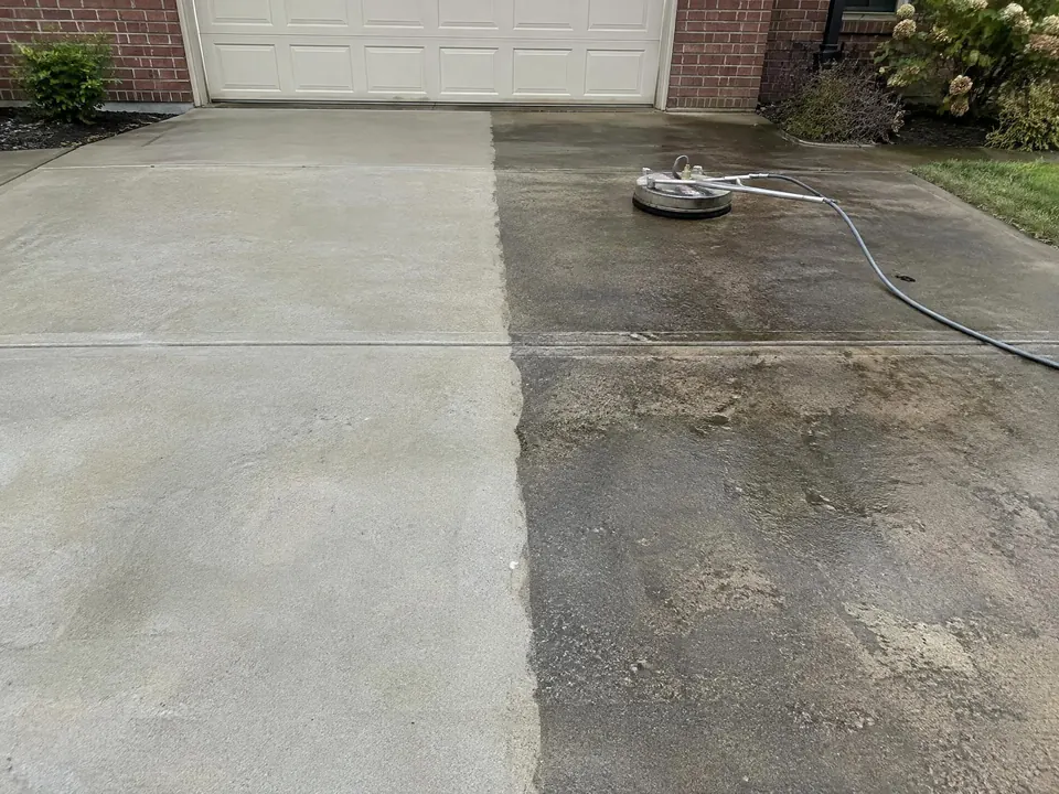 Concrete driveway half pressure-washed, showing clean and dirty sections