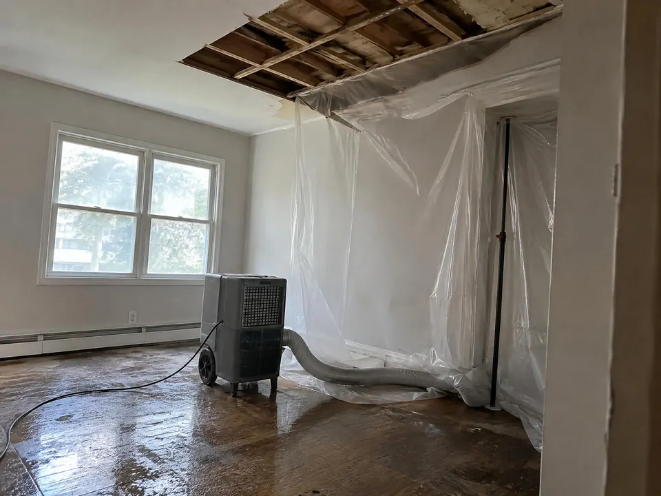 Water-stained ceiling opened up above a running commercial dehumidifier